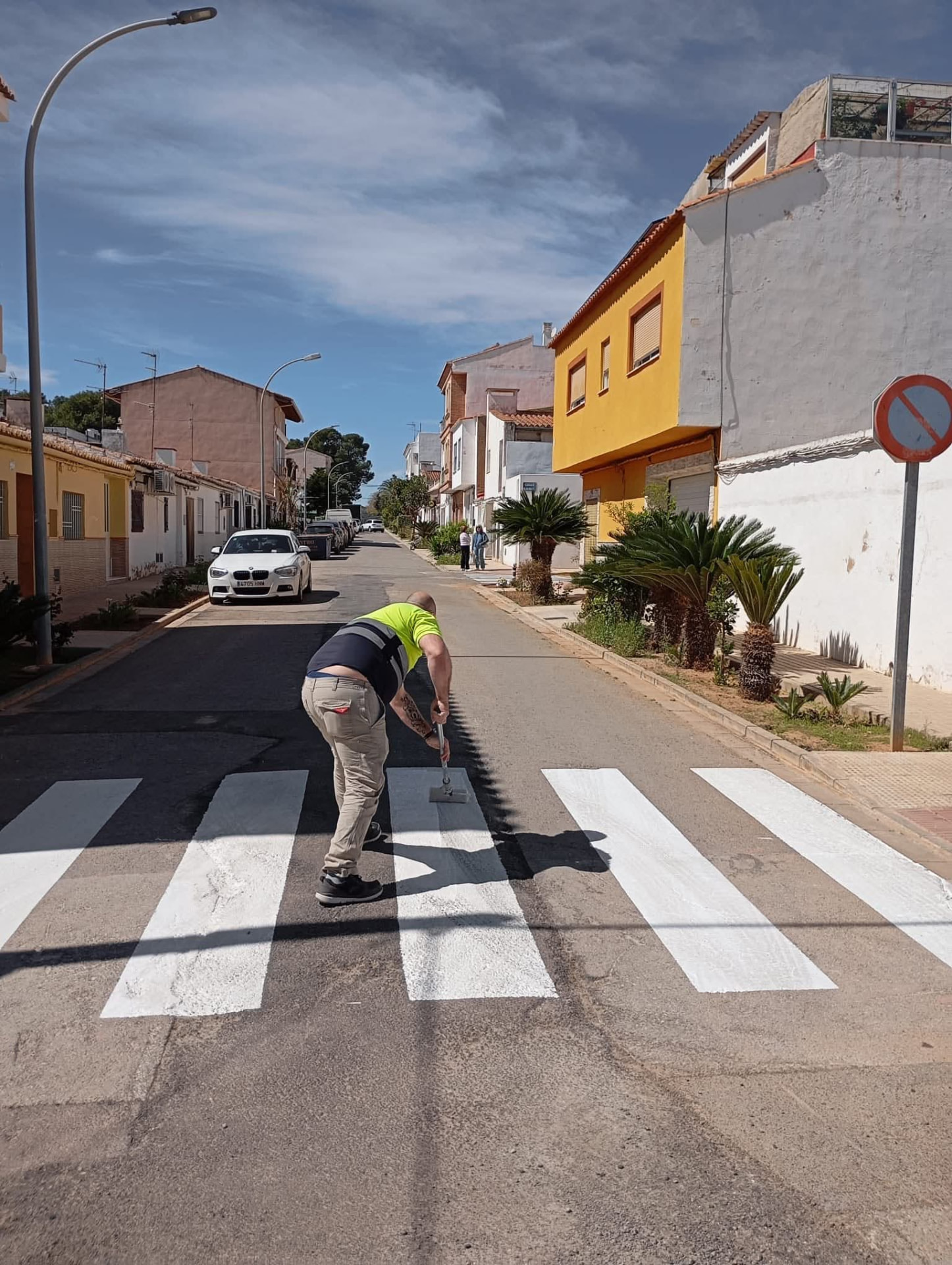 Operario municipal repintando un paso de peatones en una calle del municipio.