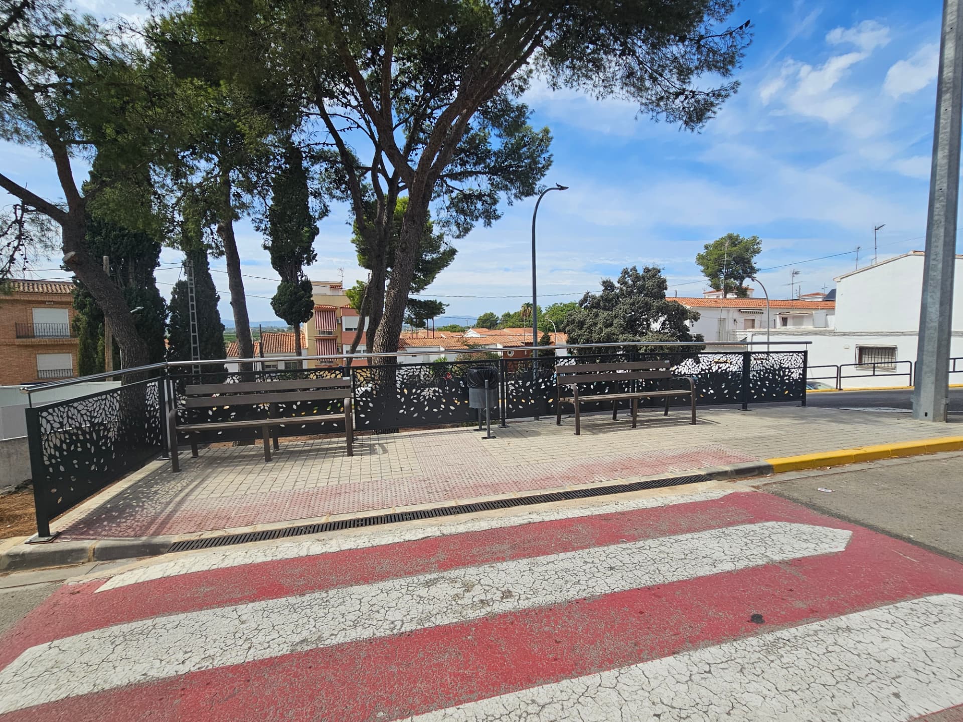 Mirador con bancos y barandilla de protección junto al paso de peatones.