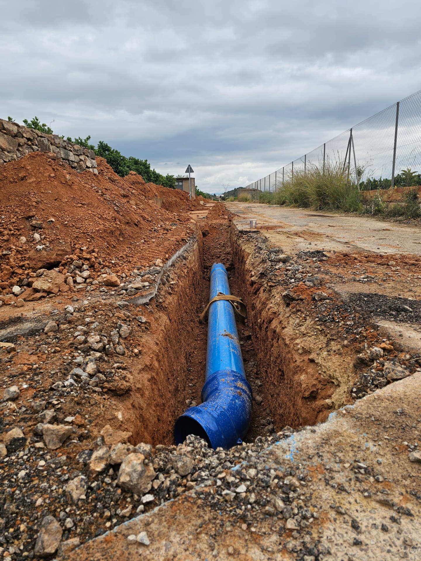 Tubería de PVC azul instalada en una zanja de tierra durante la sustitución de la conducción general de abastecimiento de agua potable.